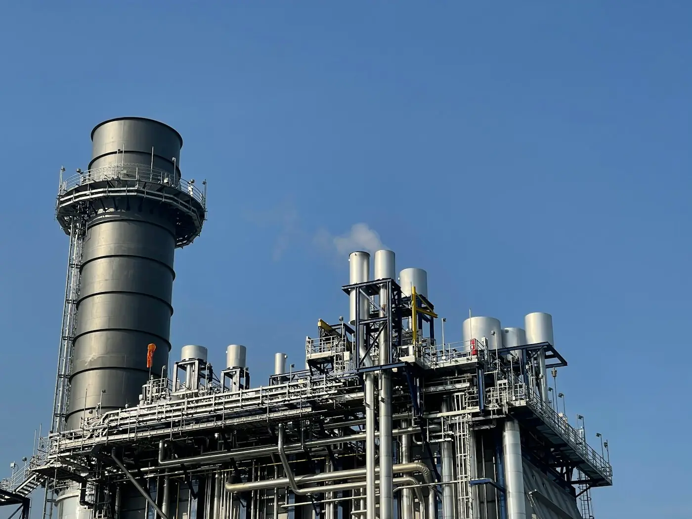 Industrial processing plant with a tall stack under a blue sky