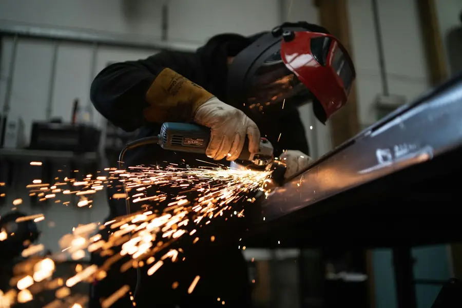Fabricator grinding steel with sparks flying