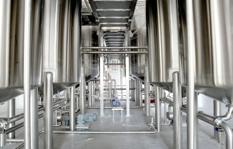 Row of stainless steel process tanks and walkways in a plant